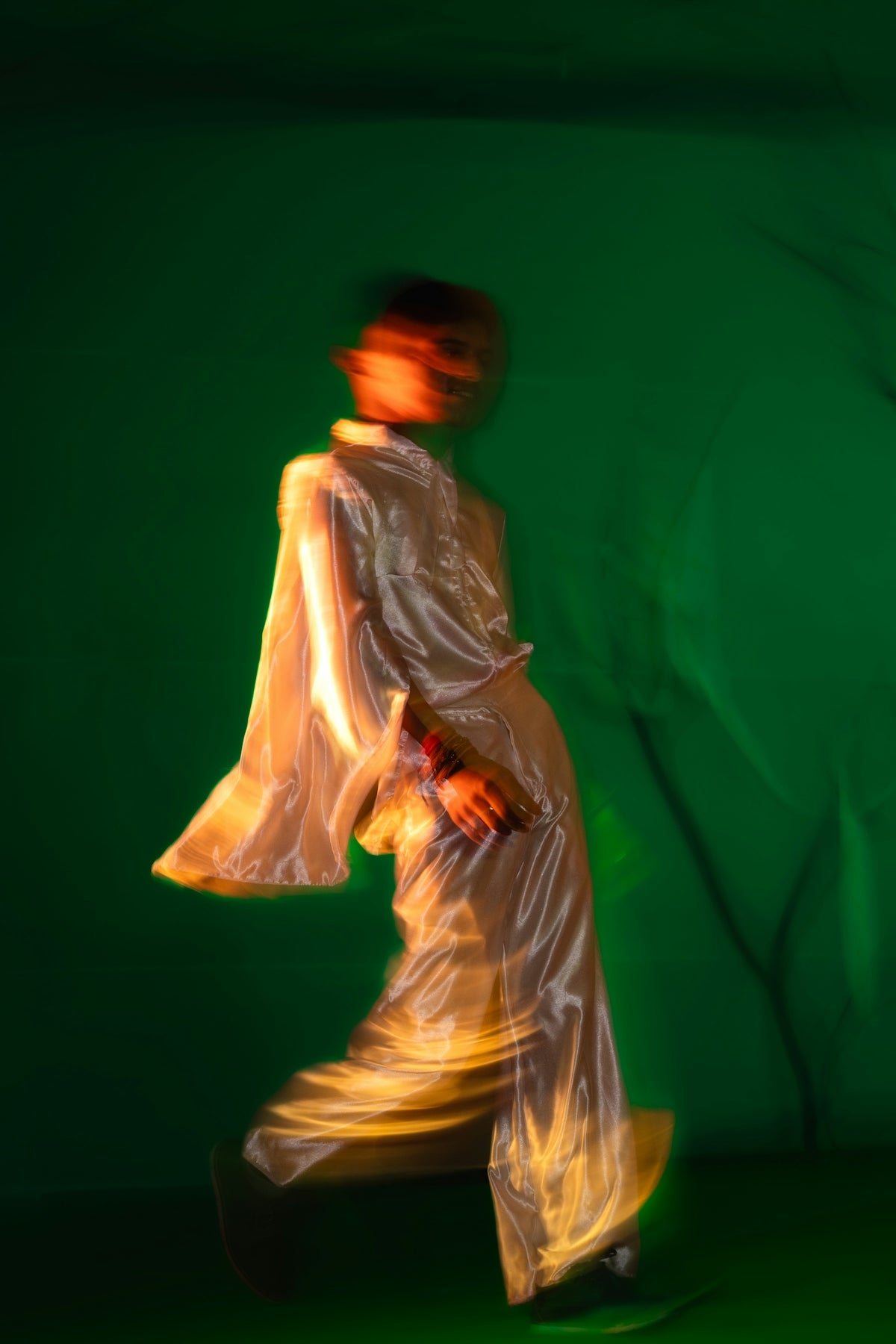 A blurred figure in white against a green backdrop